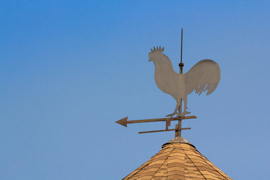 rooster air measure, chicken wind measure direction on the top of roof against blue sky.