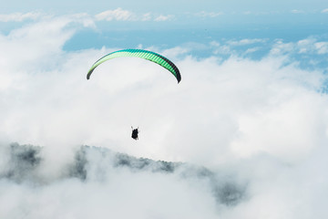 Two people are flying on a paraglider in the sky.  Tandem flight