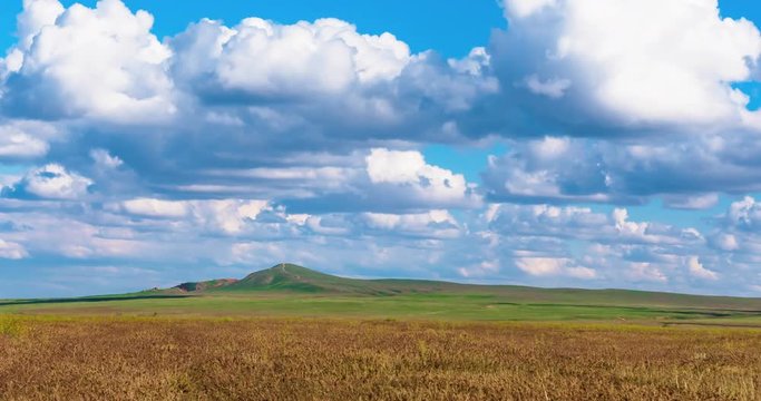 Timelapse beautiful landscape clouds over the green field 4K FULL HD Clouds float in the sky. Movement of white clouds in the blue sky. Mount Bogdo National Park.
