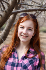Fototapeta premium Smiling red-haired teen girl in a garden