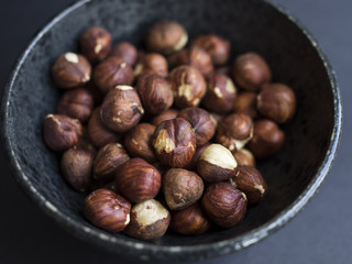 Hazelnuts in bowl on dark background
