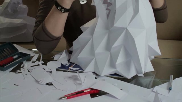 Man makes paper wolf's head.