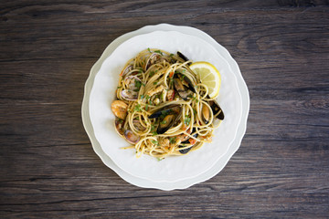 Spaghetti with seafood in white ceramic plate on wooden background