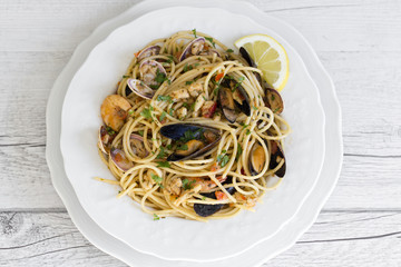 Spaghetti with seafood in white ceramic plate on wooden background