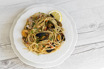 Spaghetti with seafood in white ceramic plate on wooden background
