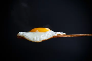 Foto op Canvas Fried egg with a wooden spoon © Peredniankina