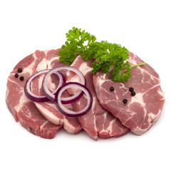 Raw pork neck chop meat with parsley herb leaves, peppercorn spices and onion slices garnish isolated on white background cutout
