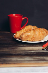 red mug, two croissants on a plate
