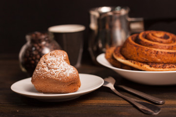 bun and cake on a plate, cup and bucket in the background