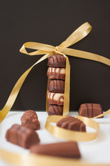 Torre di caramelle al cioccolato legati con un nastro d'oro su sfondo nero