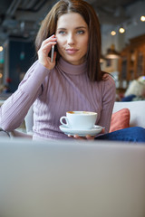 Image of young female reading sms on the phone in cafe