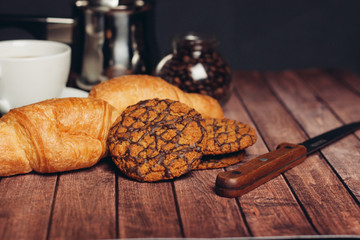 oatmeal cookies with chocolate icing and croissants on the table, sharp knife