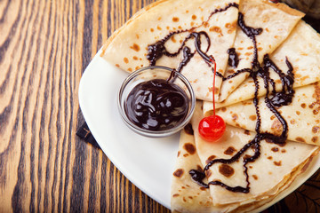 Pancakes with chocolate sauce on wooden background
