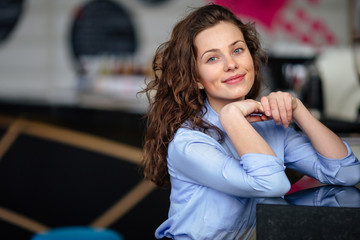 Pretty girl sitting near the table with cup of coffee and smile to camera