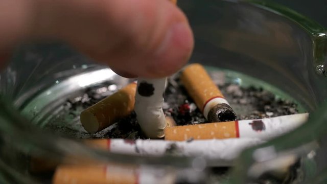 man puts a cigarette in an ashtray