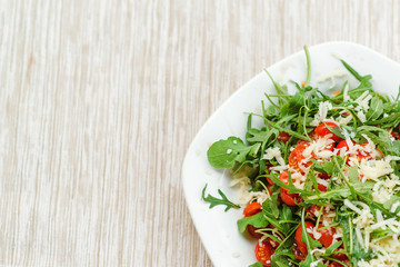 Fresh salad with tomato, ruccola on a kitchen table.
