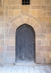 Wooden aged vaulted ornate door and stone wall, Medieval Cairo, Egypt