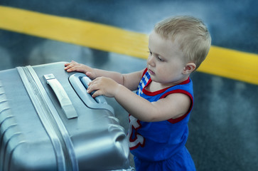 Little Boy in blue suit with silver suitcase at the airport