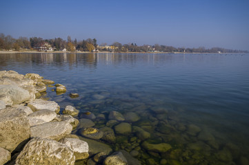 Fototapeta premium Bodensee Region im Frühjahr mit Steinen am Seeufer und Sonnenschein