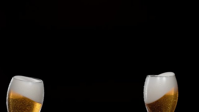 Having a toast with two glasses of beer and spilling. Shot with high speed camera, phantom flex 4K. Slow Motion.