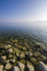 Steine am schönen Seeufer des Bodensee mit Sonnenschein und blauen Himmel