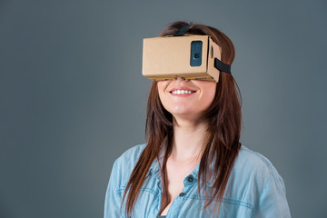 Woman using a new virtual reality headset on grey background