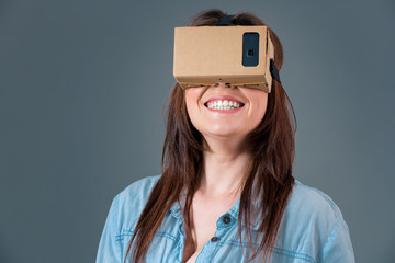 Woman using a new virtual reality headset on grey background