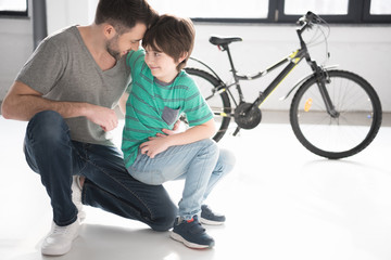 Happy father and son hugging near new black bicycle