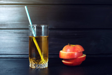 Glass of Apple juice with sliced Apple is on dark wood
