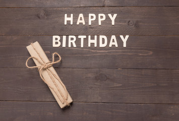 Obraz premium Happy Birthday and gift box on wooden background with copy space