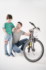 Happy father and son with new bicycle on white