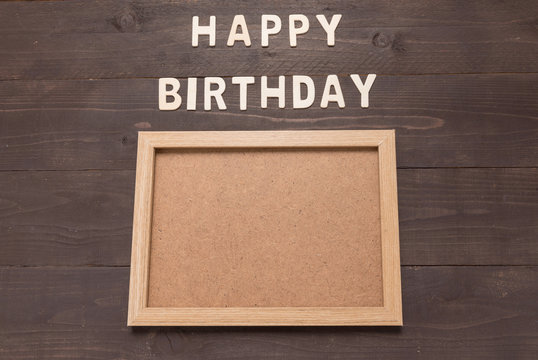 Happy Birthday and frame picture on wooden background with copy space.