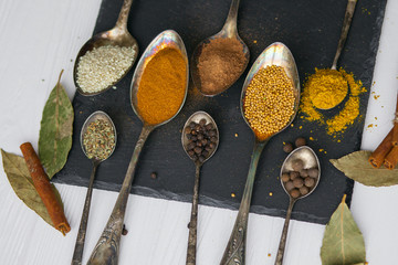 spoons with different colored spices on stone 