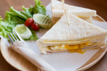 slice ham cheese egg sandwich breakfast with fresh vegetable cucumber on wooden table ,selective focus