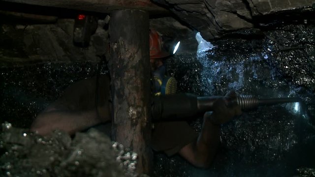 Miner produces coal at depth in the mine using a jackhammer