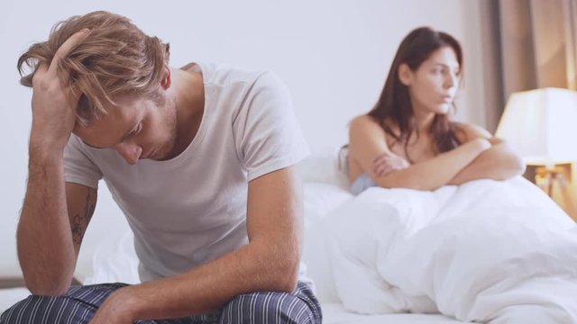 Young sad Caucasian pair quarreling in the morning sitting in bed in slowmotion