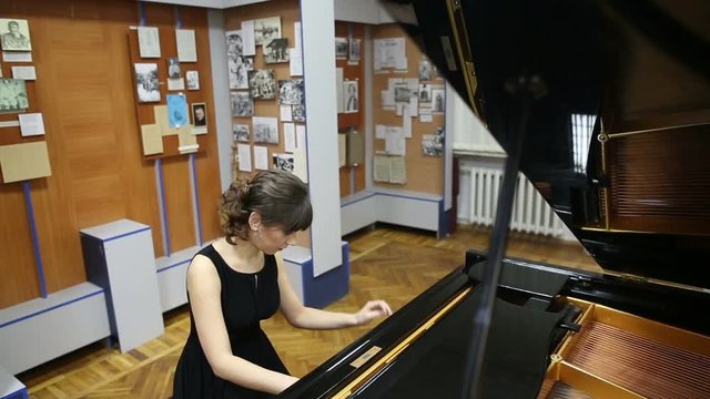 Happy talented young lady playing grand piano. Pianist musician plays piano at a concert, fingers touching piano keys. Fingers typing on piano keys
