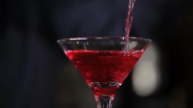 Barman pouring a cocktail into a glass