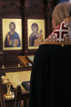 Orthodox Bishop Praying In Front Of Altar Icons