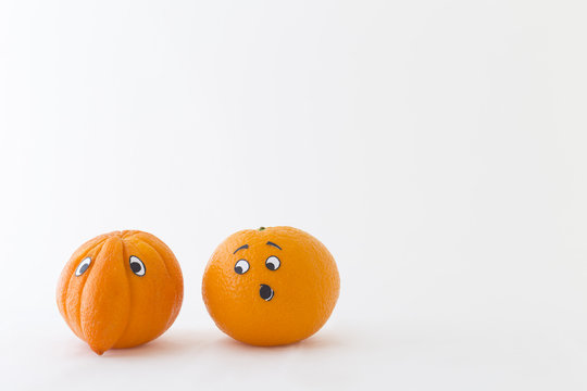 Fresh oranges with funny faces in front of white background. One orange has a huge nose