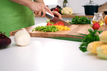 Close up of  woman's hands cooking in the kitchen. Housewife slicing ​​fresh salad. Vegetarian and healthily cooking concept