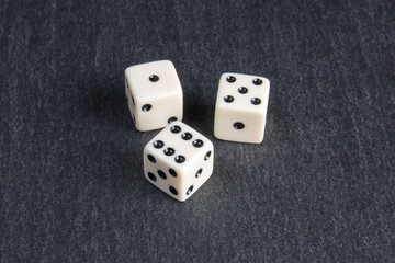 small dice on dark stone background	