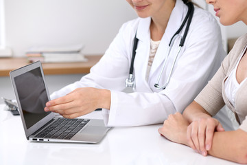  Close up of a doctor and  patient  sitting at the desk. Physician pointing into laptop computer. Medicine and health care concept