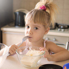 Little blonde girl is preparing to eat in the home kitchen. Preparation for sweet baking ingredients. Eggs. Chocolate. Butter. Cooked with his own hands.