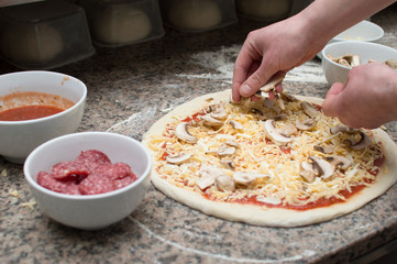 Cook in the kitchen putting the ingredients on the pizza. Pizza concept. Production and delivery of food.