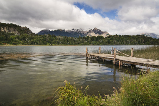 A wooden dock leads the eye to a small mountain lake; Bariloche, Argentina