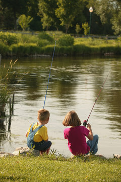 Boy And Girl Fishing On Lakeshore In The Midwest