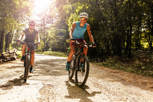 Two mountain bikers riding bike in the forest on dirt road.