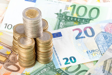 Euro coins stacked on euro banknotes background.