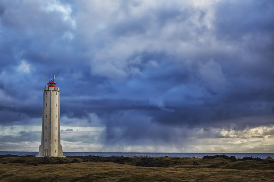 Lighthouse known as Malarrif on the Snaefellsness Peninsula with rain squall falling in the background; Iceland